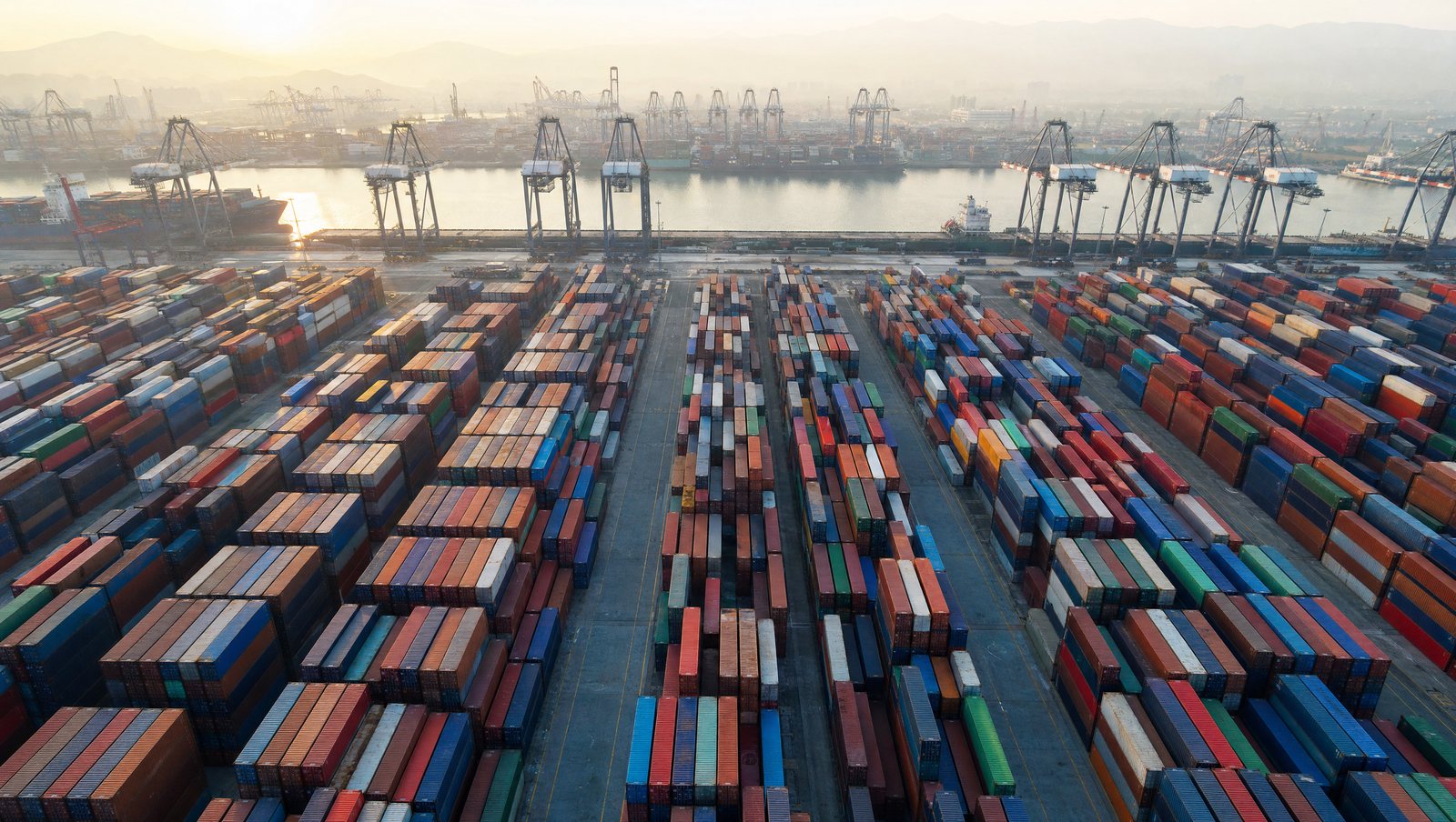 Aerial view of a container port with stacked shipping containers and gantry cranes